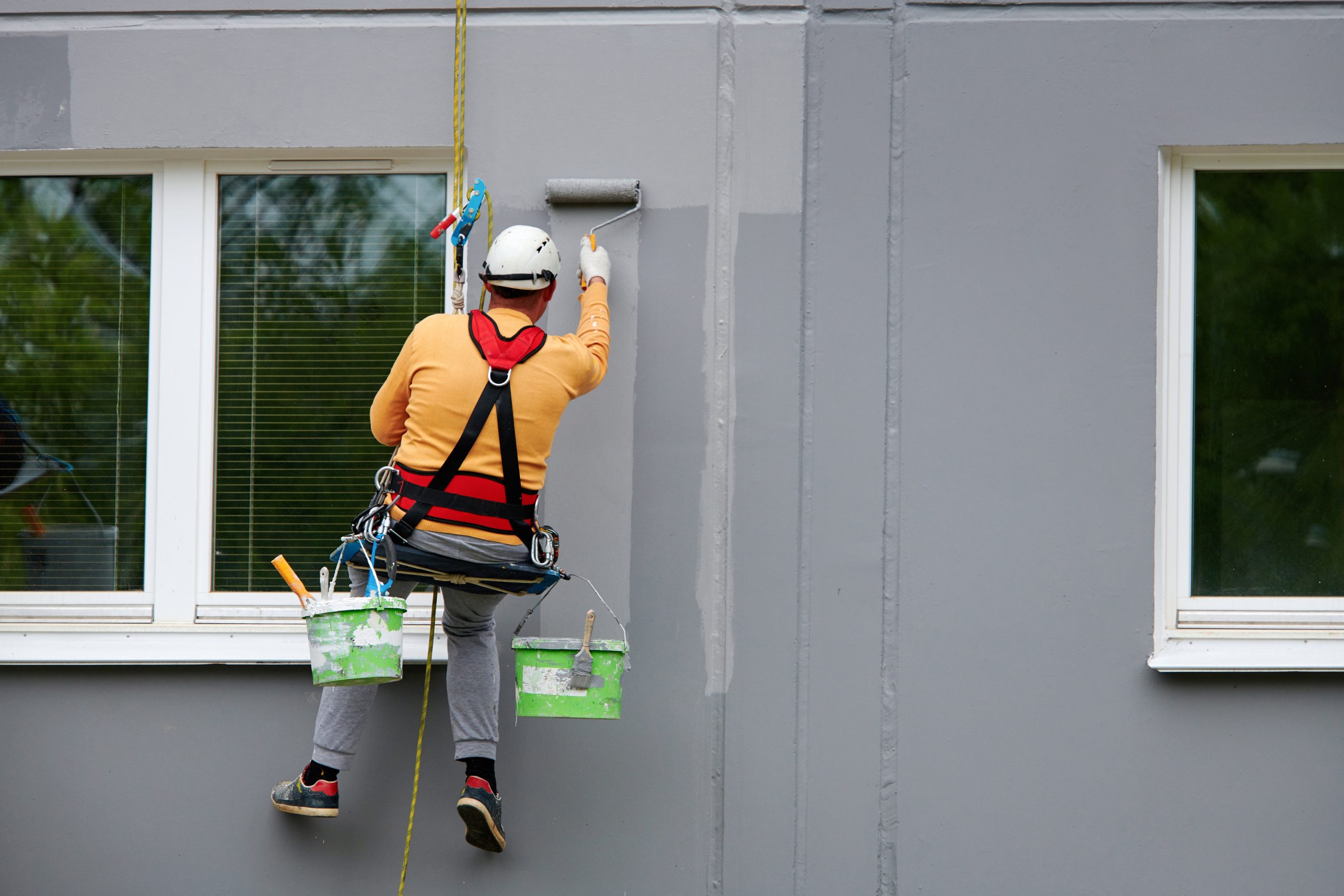 trabajador realizando labores de mantenimiento a fachada en altura scaled